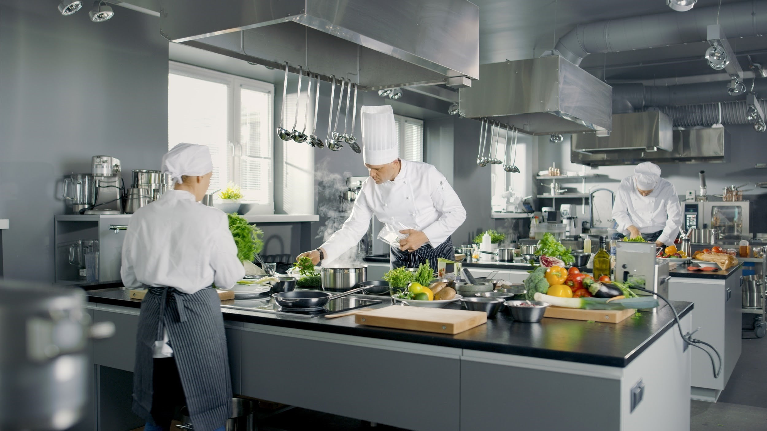 Kucharze pracujący w nowoczesnej profesjonalnie wyposażenie kuchni gastronomicznej