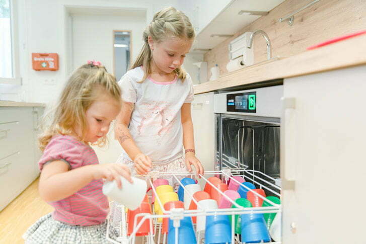 Dzieci wkładają naczynia do zmywarki – wynajmijzmywarke.pl